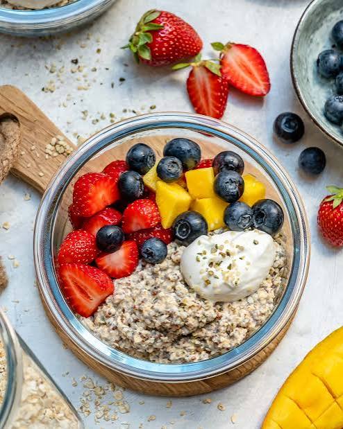 A bowl of overnight oats topped with strawberries, blueberries and mango