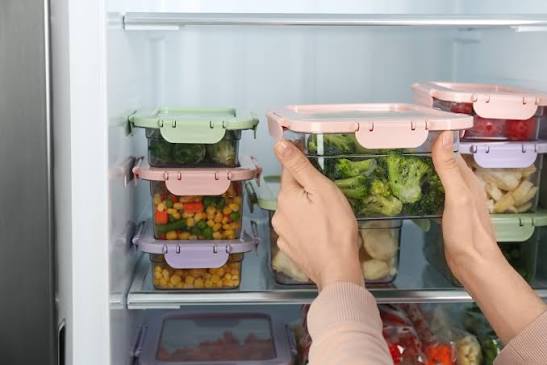 Stacked food storage containers of prepared vegetables inside a fridge